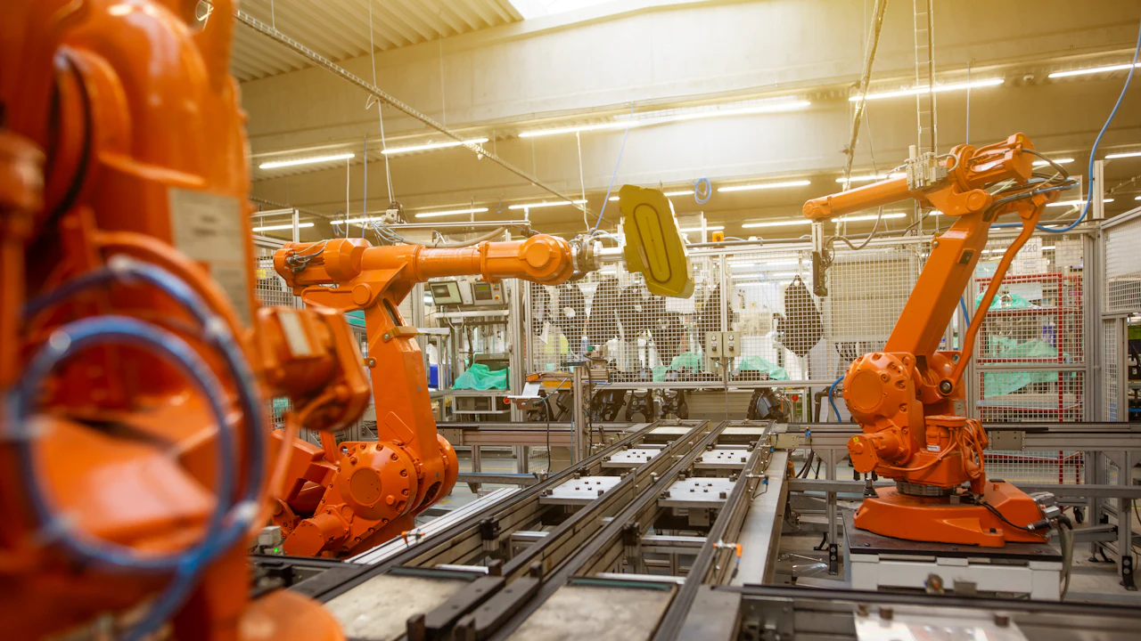 A factory floor with orange robot arms